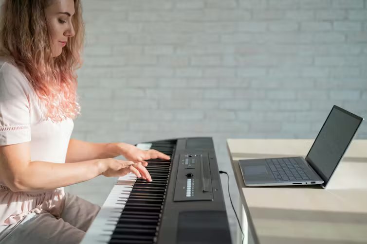 A young woman focuses on playing an electric piano