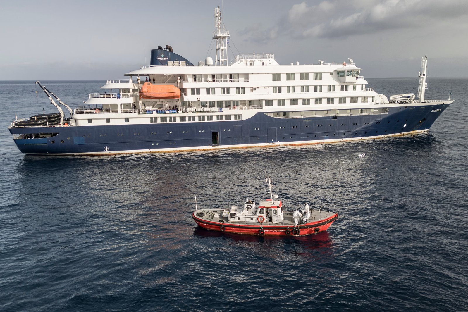An ambulance boat carries crew members wearing hazmat suits to the Dutch cruise ship MV Hondius near Cape Verde this week, the site of a deadly outbreak of hantavirus. Experts say summer travelers should be aware of four common cruise illnesses before they set sail