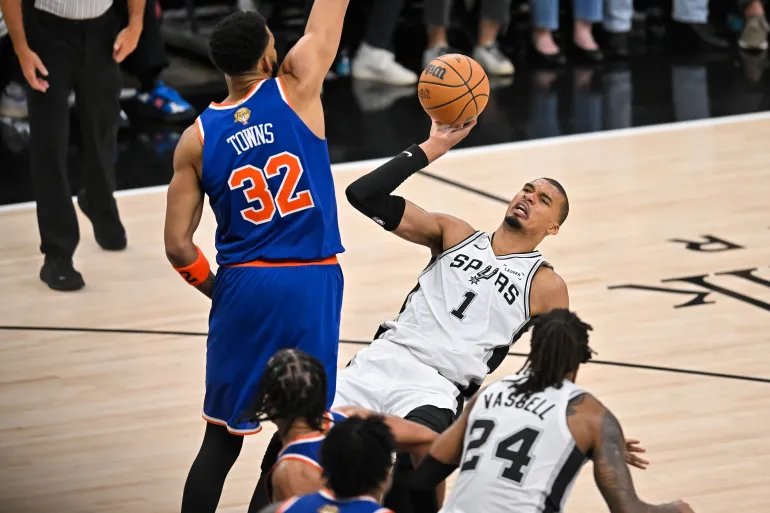 San Antonio Spurs forward Victor Wembanyama (1) is fouled by New York Knicks center Karl-Anthony Towns (32) during the second half of Game 5 of the NBA Finals basketball series, Saturday, June 13, 2026, in San Antonio. (AP Photo/Darren Abate)