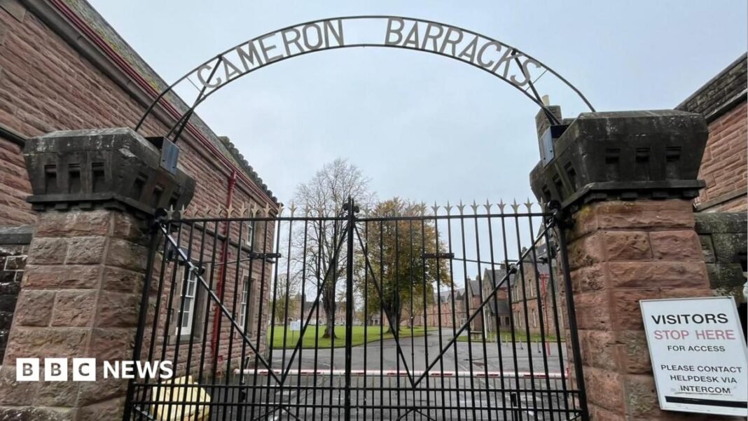 The barracks is a group of traditional, brick-built buildings with long narrow windows with white frames. The complex is surrounded by a high, wire fence.