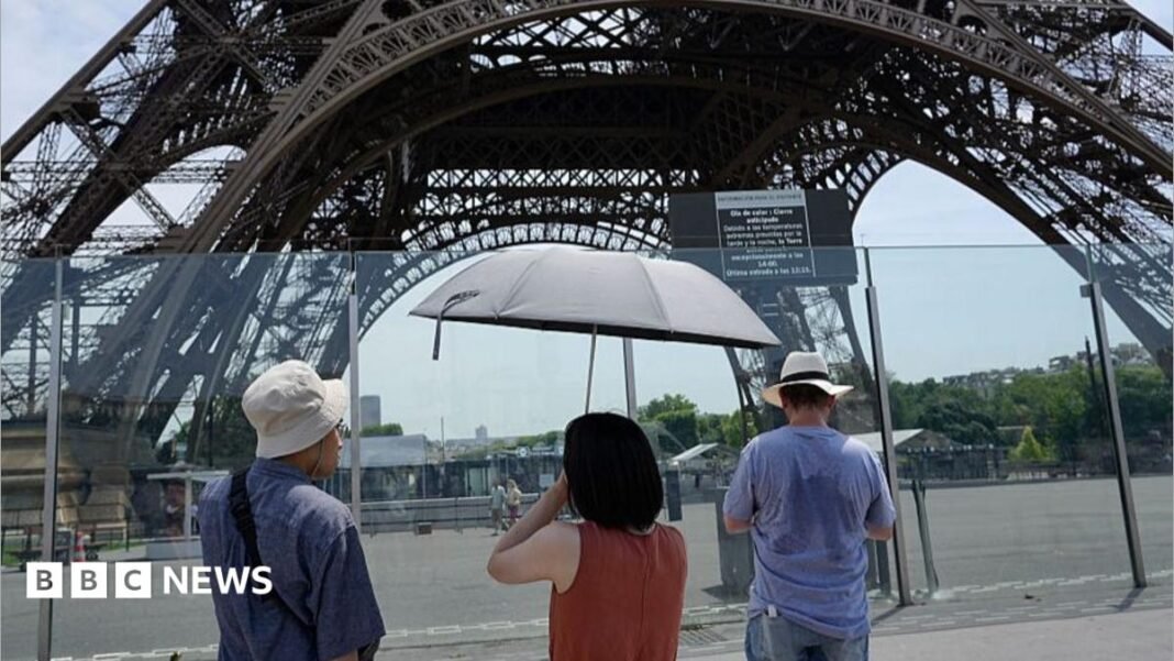 Power outages hit France as record heatwave set to peak A woman keeps cool by a fan in her home wearing a red dress