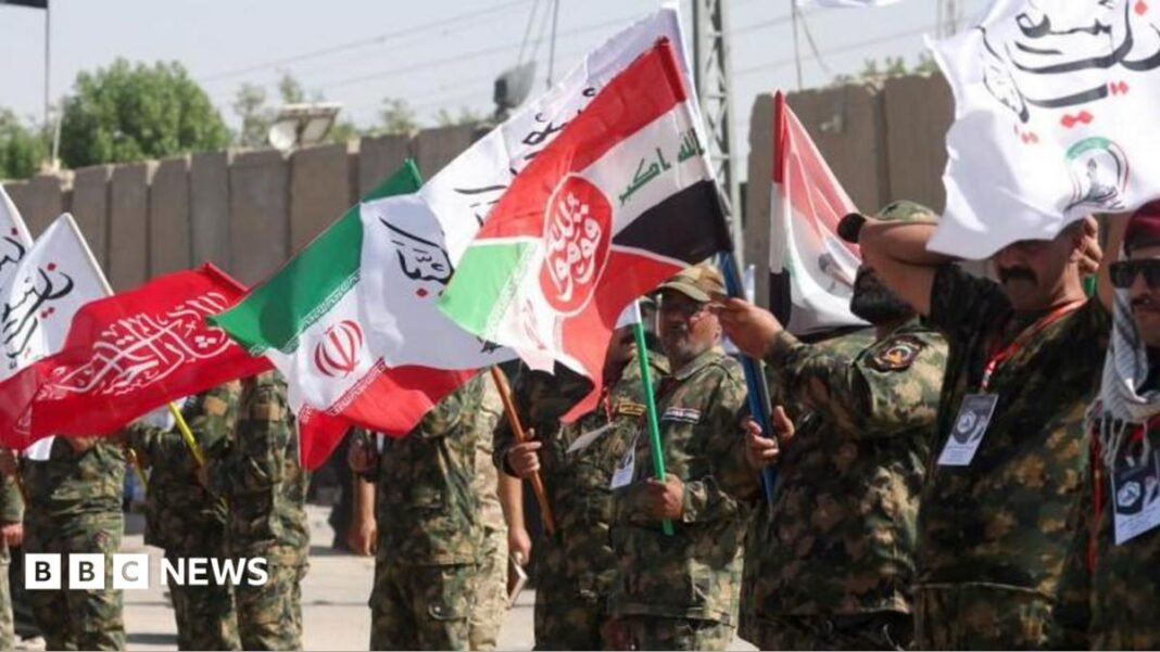 Iranian military personnel stand in a line waving red, white, green and black flags.