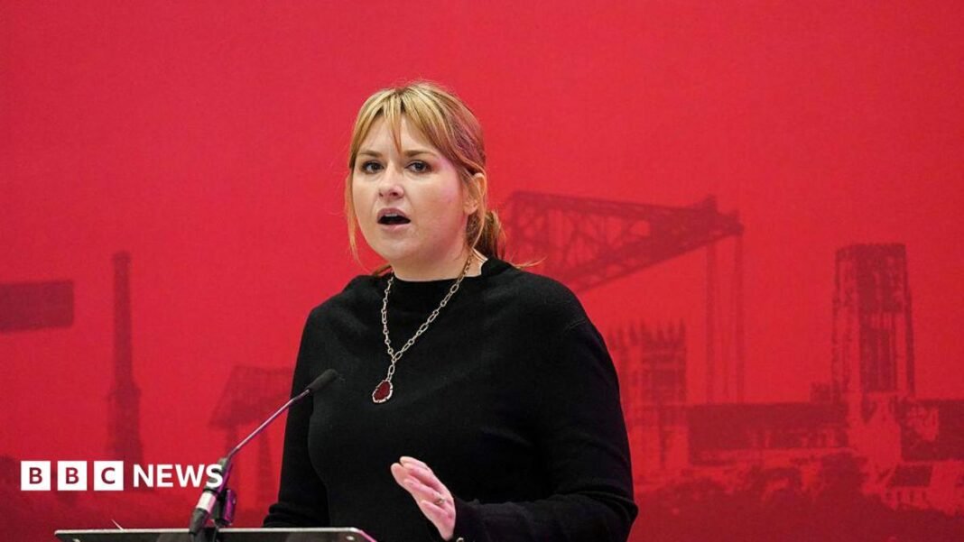 Labour general secretary Hollie Ridley making a speech. She is wearing a black dress with a necklace. 
