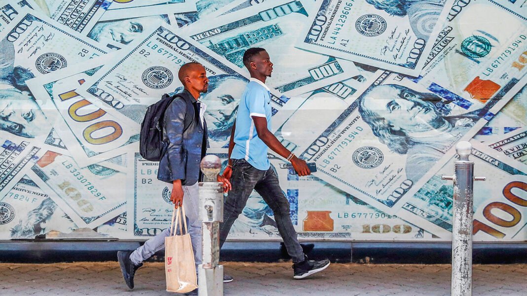 People walk past an image of U.S. dollar bills outside a currency exchange bureau in downtown Nairobi, Kenya