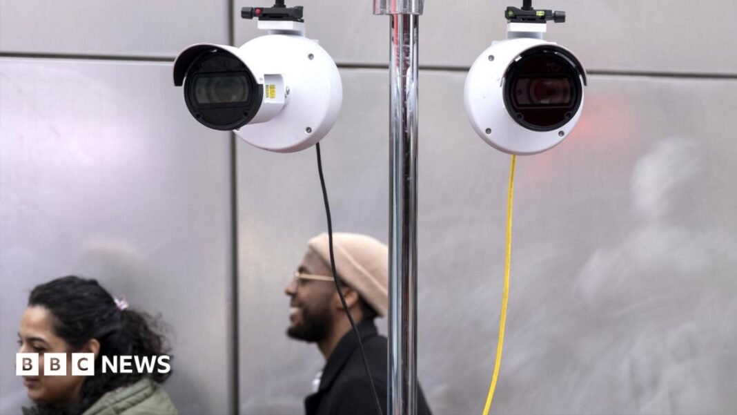Three spherical black cameras are shown, hoisted on a post on top of a police van. In the background is the Union Jack bunting of Regent Street, by Oxford Circus tube station.