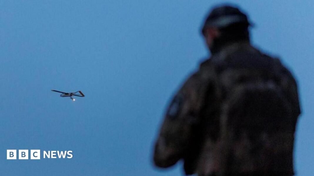 A Ukrainian soldier operating a drone, which is flying in the air in the background