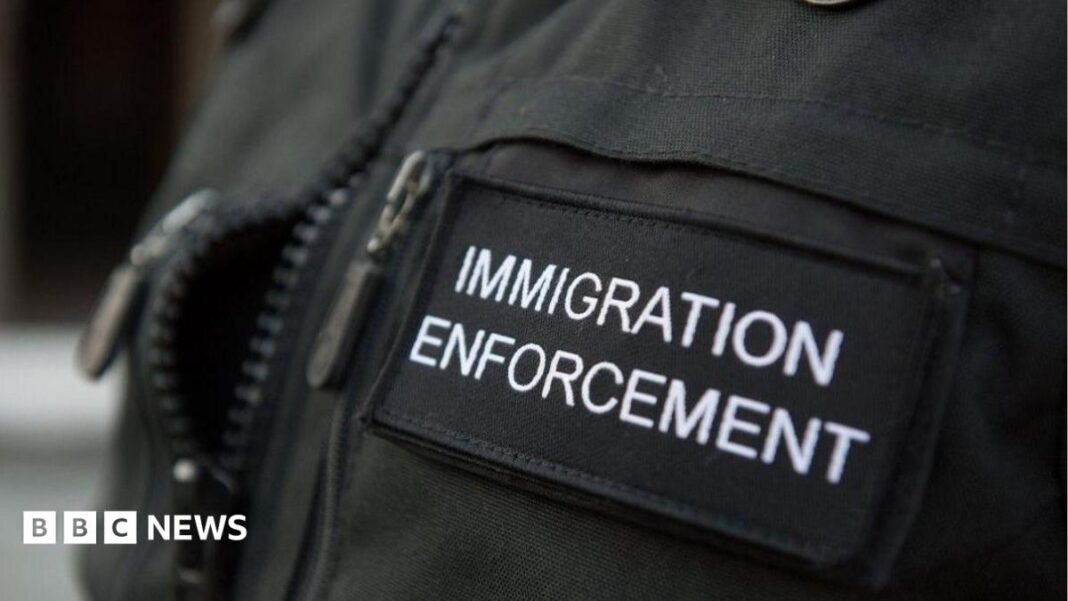 A close-up shot of the badge of an Immigration Enforcement officer, photographed during a raid a residential property looking for illegal immigrants in London  
