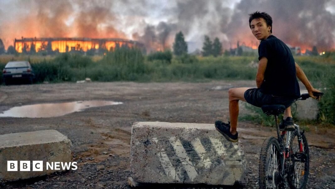 Rescuers work at the site of a Russian missile strike on a goods storage in Kyiv. A large stream of water can be seen coming from a hose one of the individuals is holding.